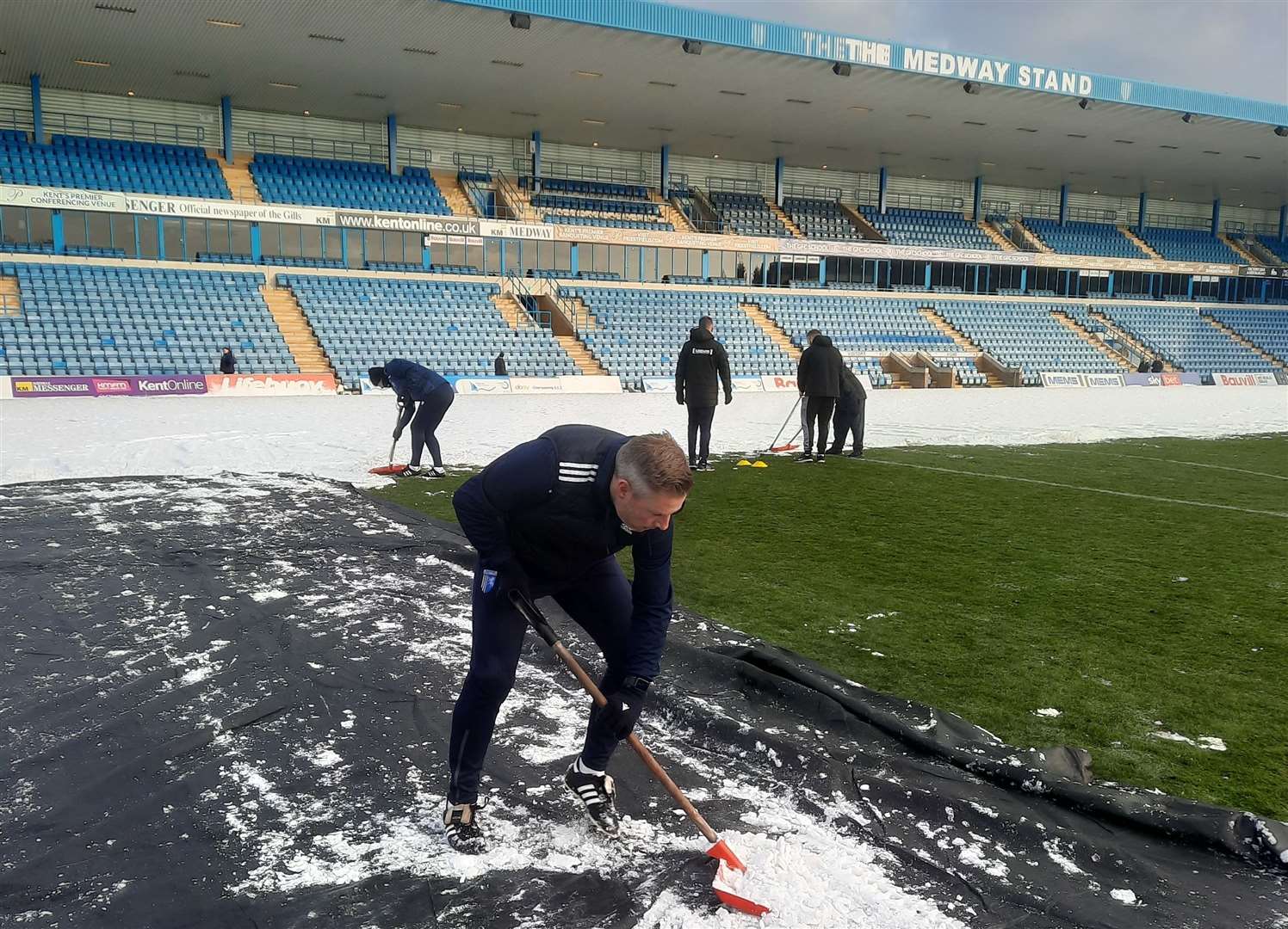 Gillingham manager Neil Harris clears snow off the Priestfield pitch so his team can train. Picture: GFC