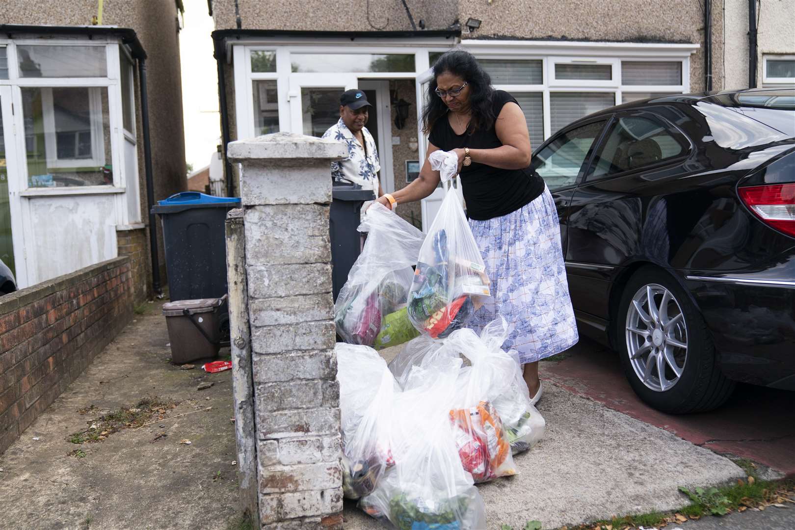 Residents Rose and Kes Bala dispose of spoiled food on their return home (Kirsty O’Connor/PA)