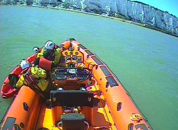 Crew help the man who had a fishing hook in his hand onto the lifeboat