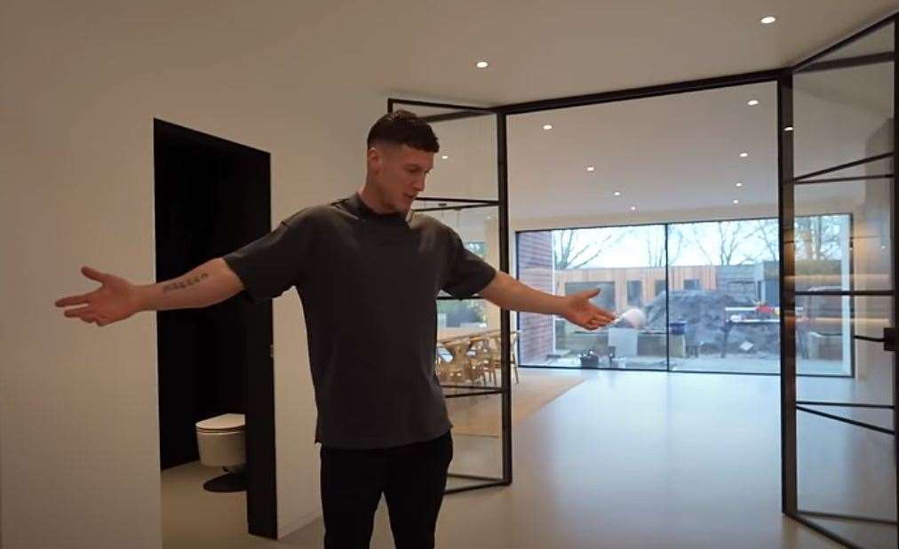Matt spreads his chiselled arms in the open-plan property. Pic: YouTube/MattDoesFitness