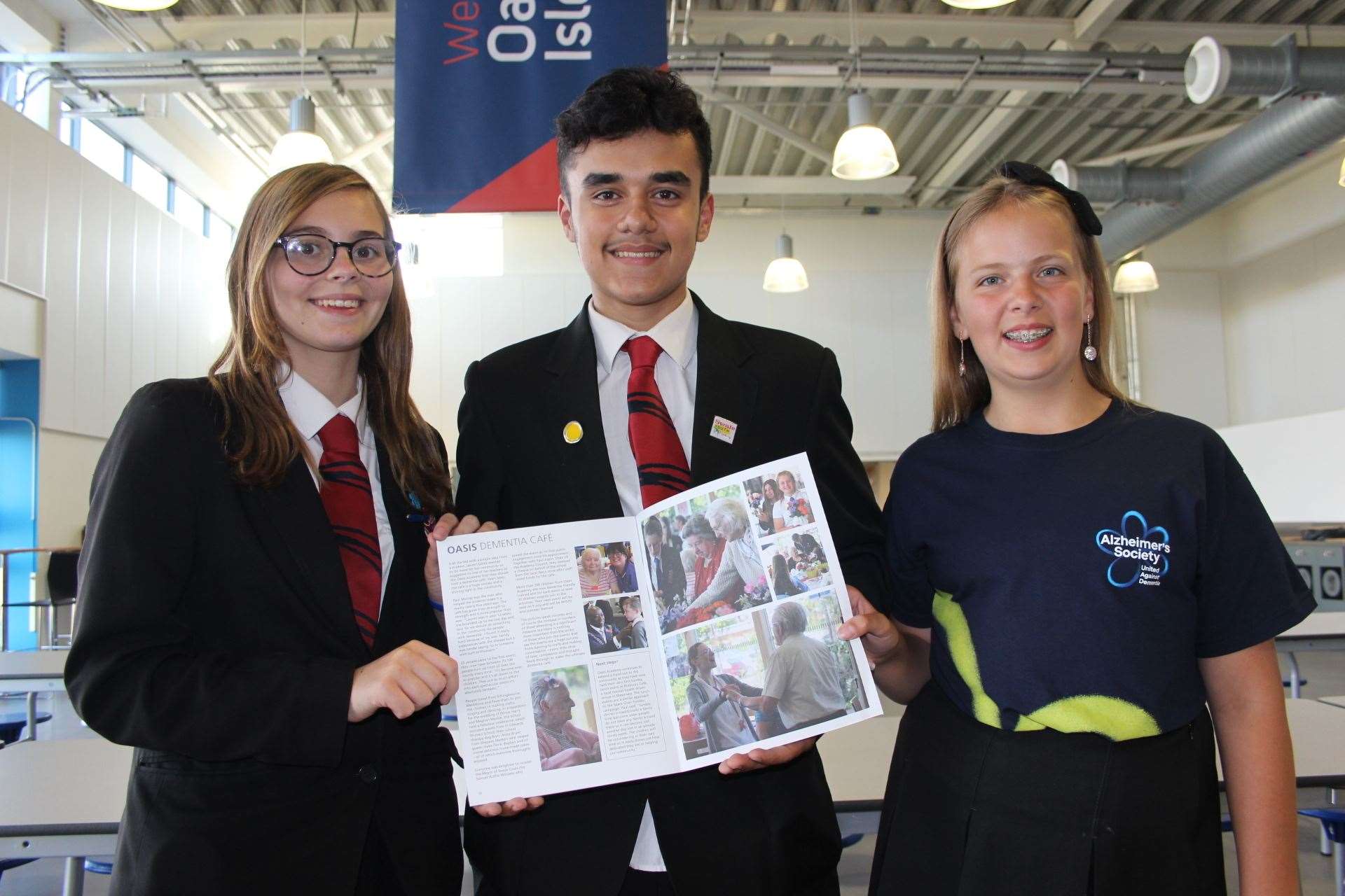 Oasis Academy students Sinead Hubbard, 14, (left) Emre Huseyin, 14, and Lucy Brightman-Stokes, 11, celebrate the Sheppey school's dementia cafe getting a double-page spread in the NHS 70-year anniversary souvenir magazine (7660433)