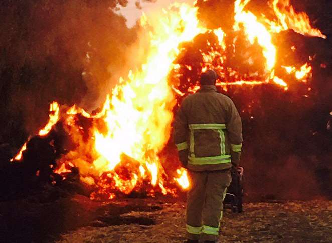 A firefighter looks on as hay goes up in smoke. Picture: @rainb0w_kitties