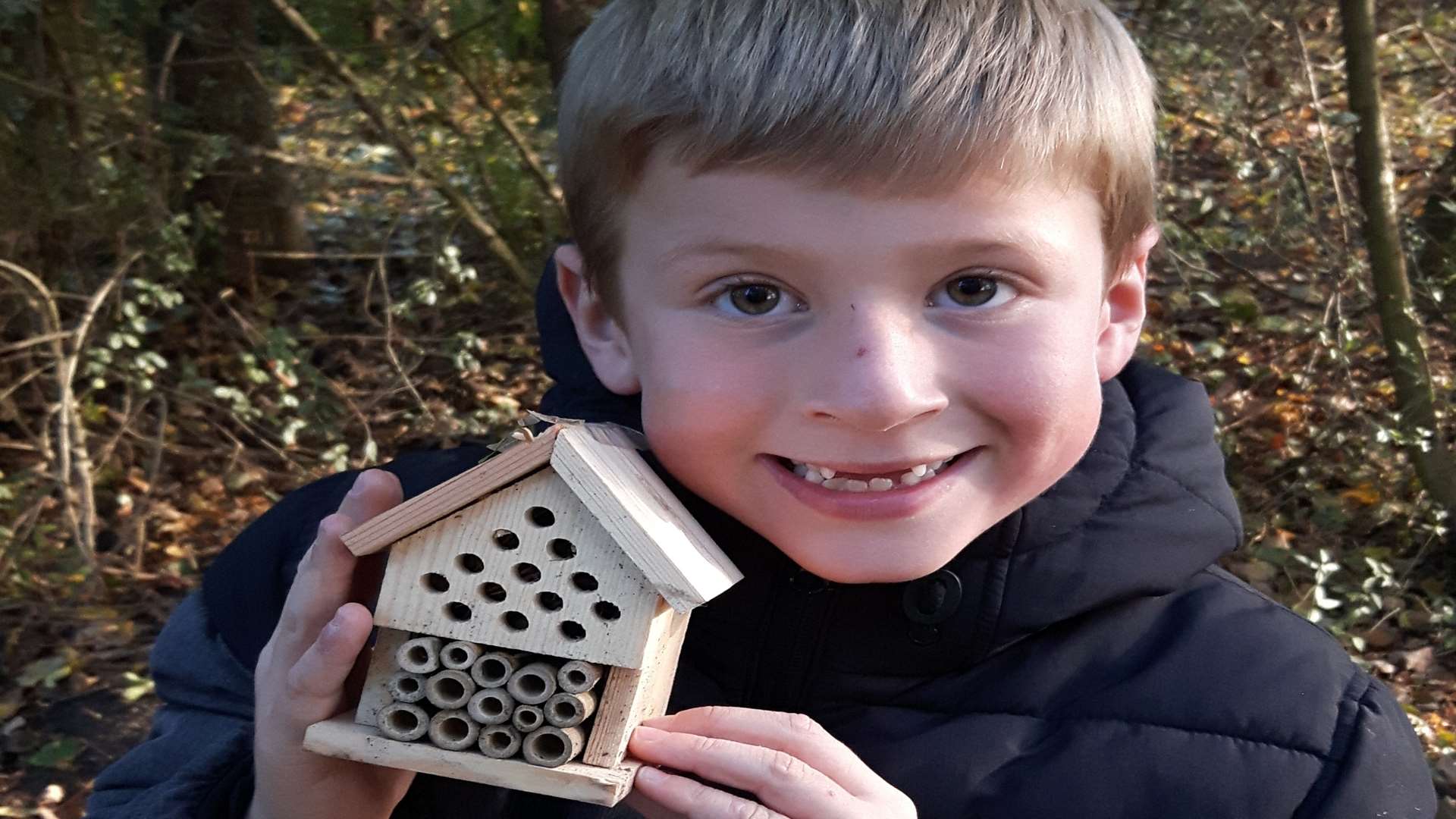 Joseph Maskrey, six, with a bug house he had made in the Green Zone. Donations of wood would help the children be able to make more items like this.