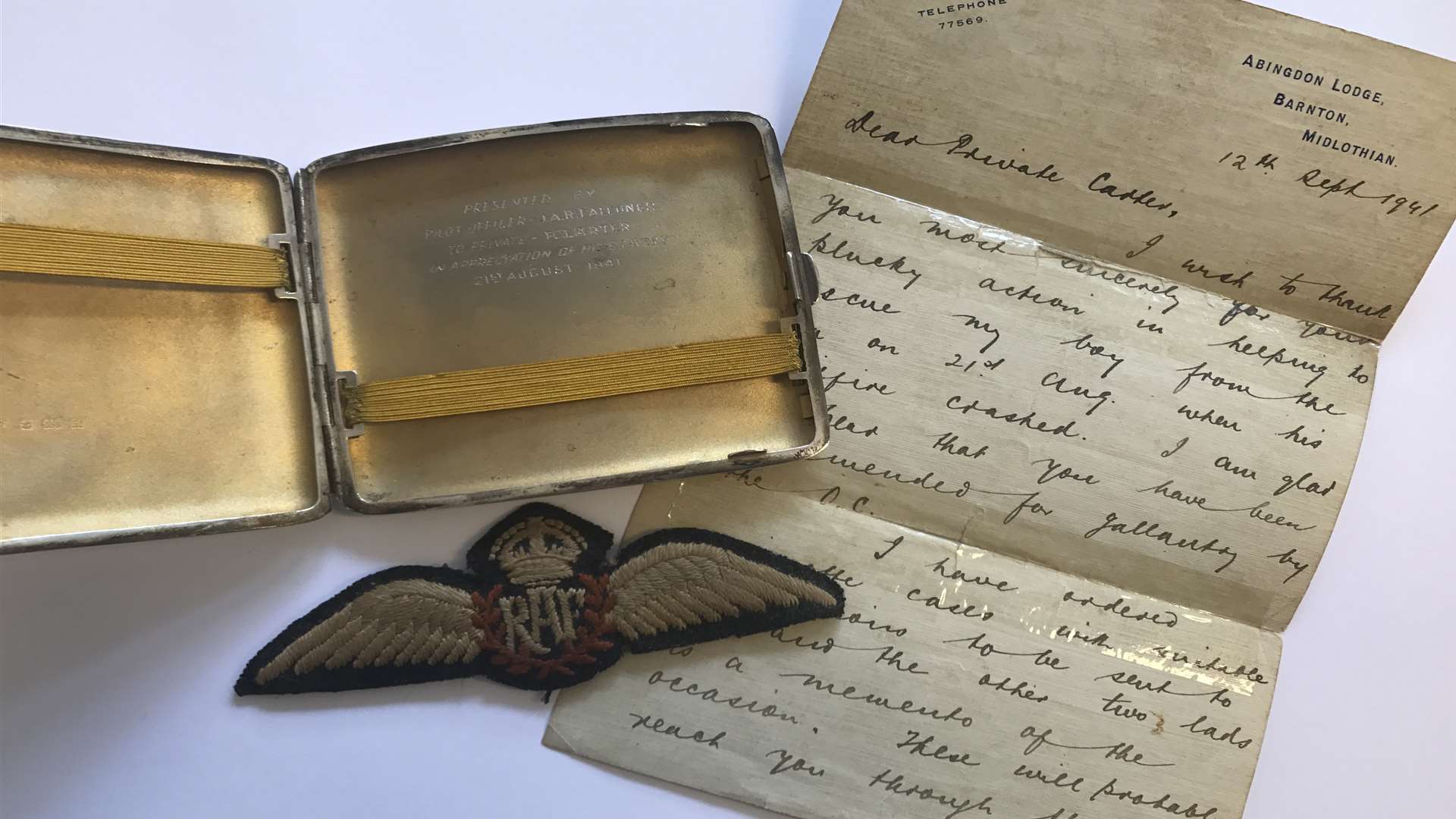 An engraved cigarette case and wings gifted to Frederick Carter for his bravery, along with a letter he received from the pilot's father