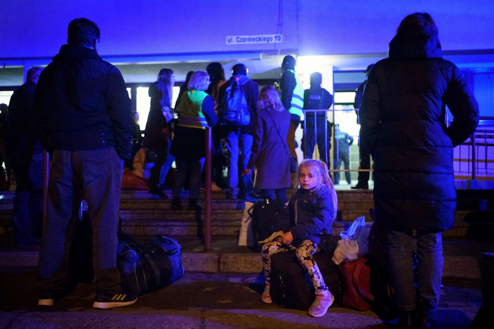 A young girl sits on a suitcase in a queue as Ukrainian refugees wait in line to board a train to return to Ukraine (Victoria Jones/PA)