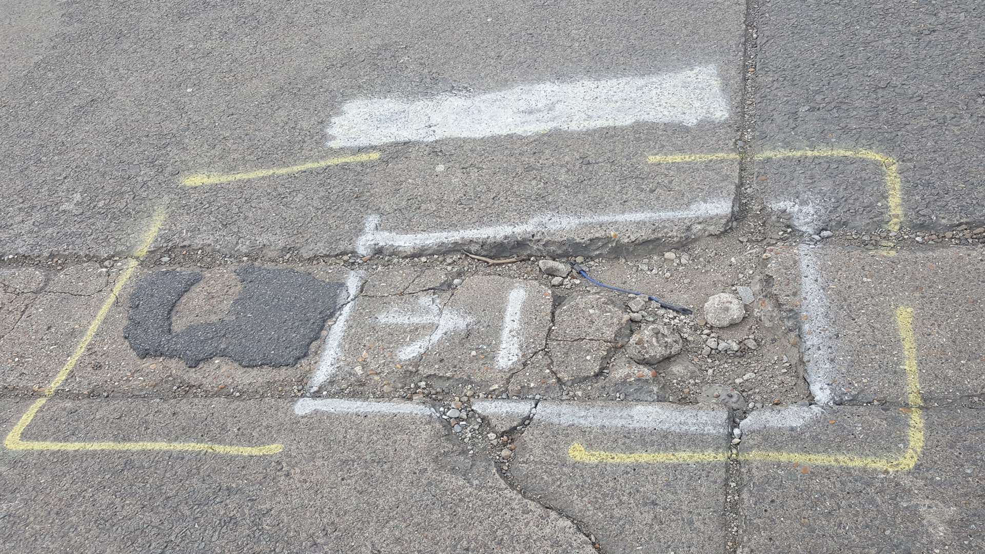 A pothole with the word 'KILLER' written over the top of it has been blocked out