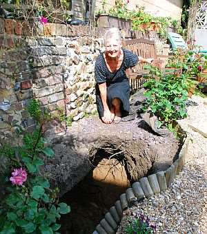 Helen Gale beside the 40 feet deep hole which opened up in the garden of her Gladstone Road home in Broadstairs after heavy rain.