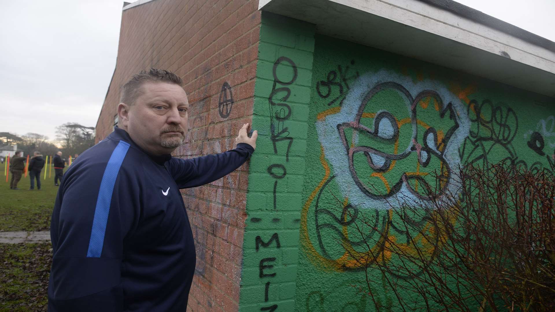 Steve Griffiths with the graffiti on Strike Force Football Club's changing rooms.