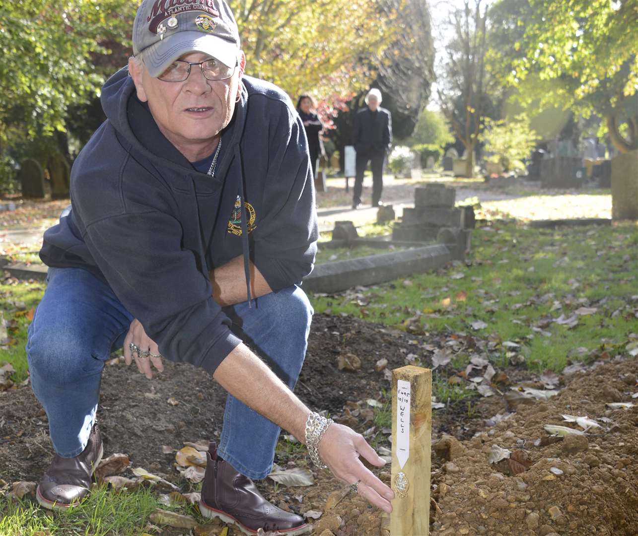 Russell Palmer puts a 1st Queens badge on the grave of Raymond Wells