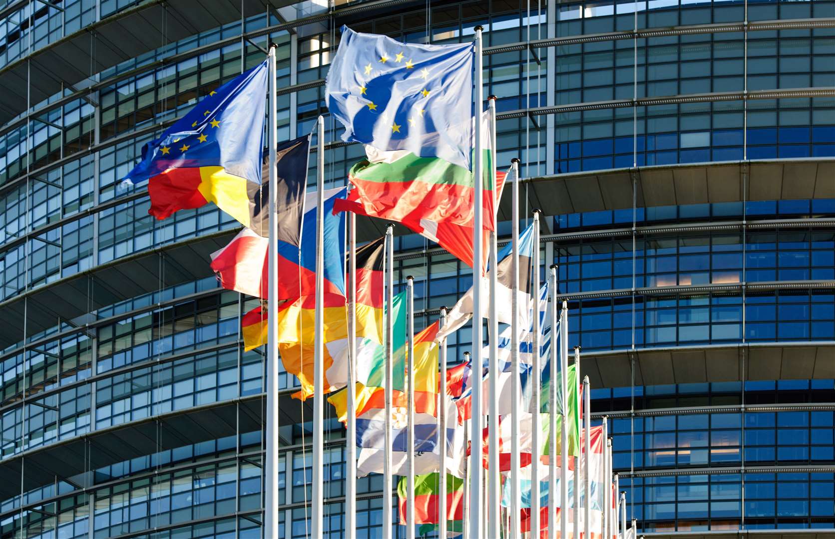 European Union flags in a row waving in front of the European Parliament building in Strasbourg