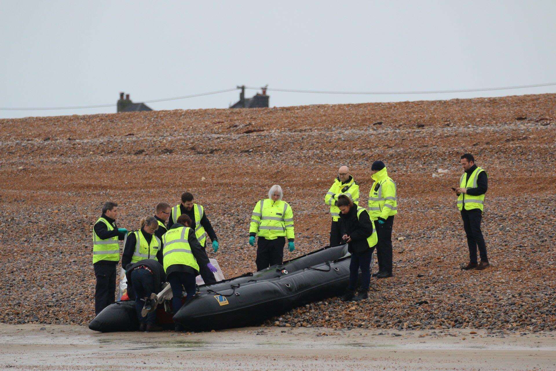 Officers wearing hi-vis National Crime Agency jackets examine a boat on the shore at Greatstone. Picture: Susan Pilcher
