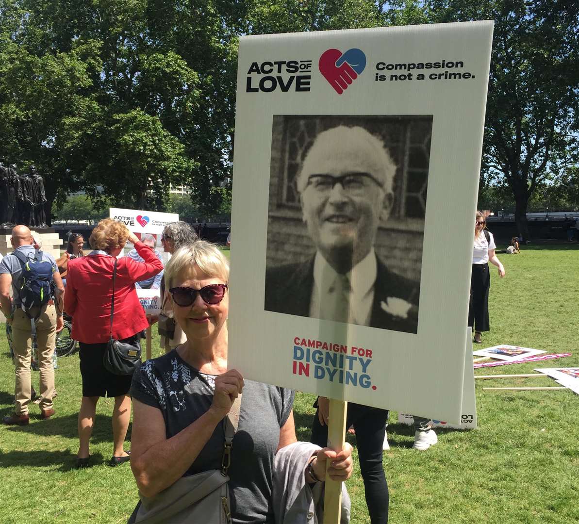 Suzanne Jee at a rally outside Parliament earlier this year, with a placard featuring a photo of her dad