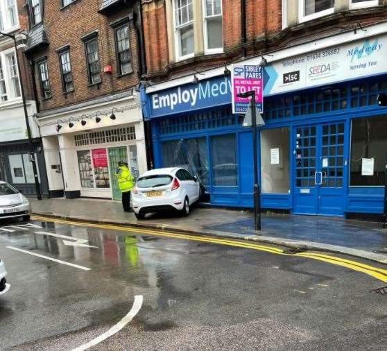 Officers were seen standing next to the car which became lodged in the shop front. Photo: @tondemazikana