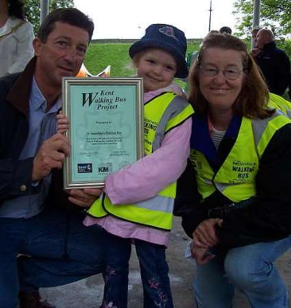 Henri Harrington of St Augustine's Walking Bus and Walking Bus child receive a six year birthday certificate for the scheme from Cllr Nick Chard.