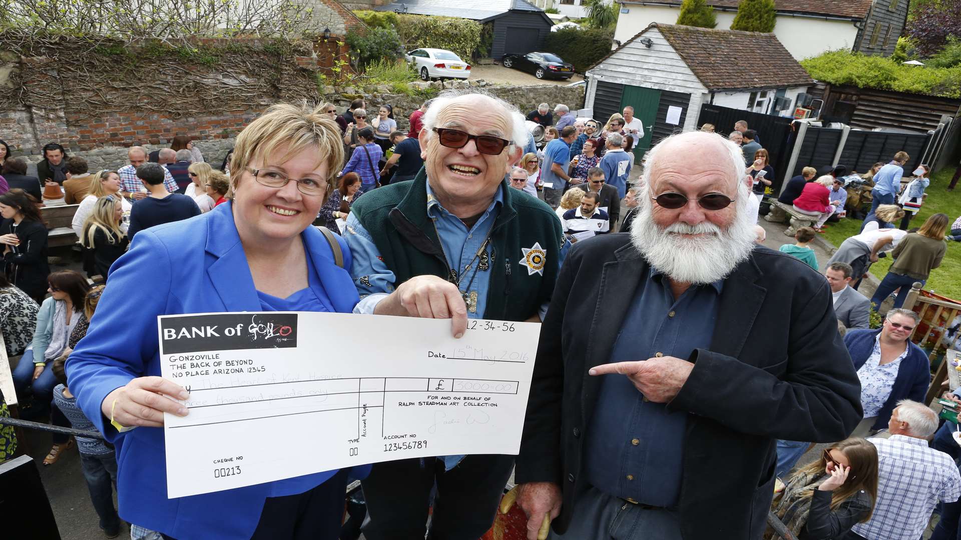 Sue Shaw accepts a cheque for £3,000 on behalf of the Heart of Kent Hospice, from Ralph Steadman, assisted by Graham Clarke