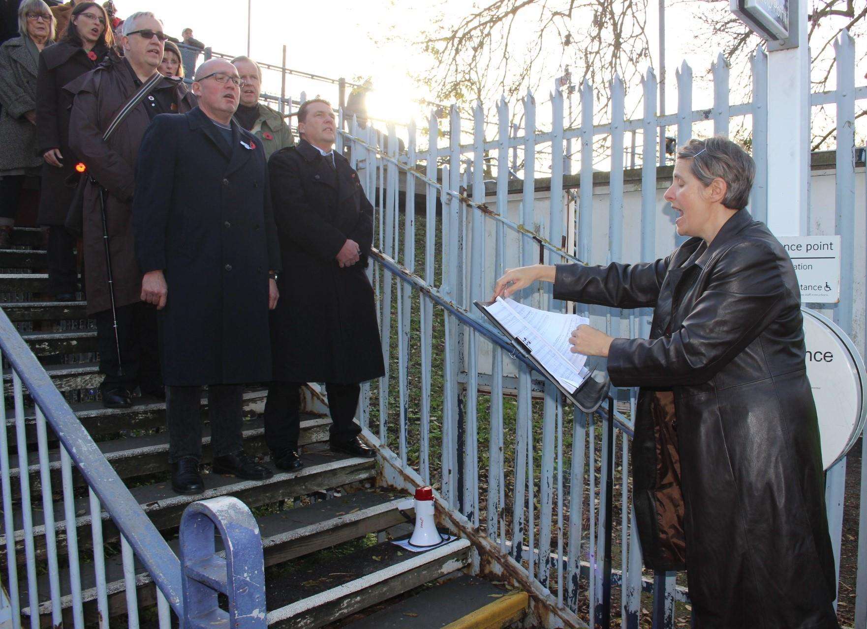 Tania Holland-Williams conducts the 55-plus choir at Queenborough train station on Sunday performing Never Again. Picture: John Nurden (5337053)