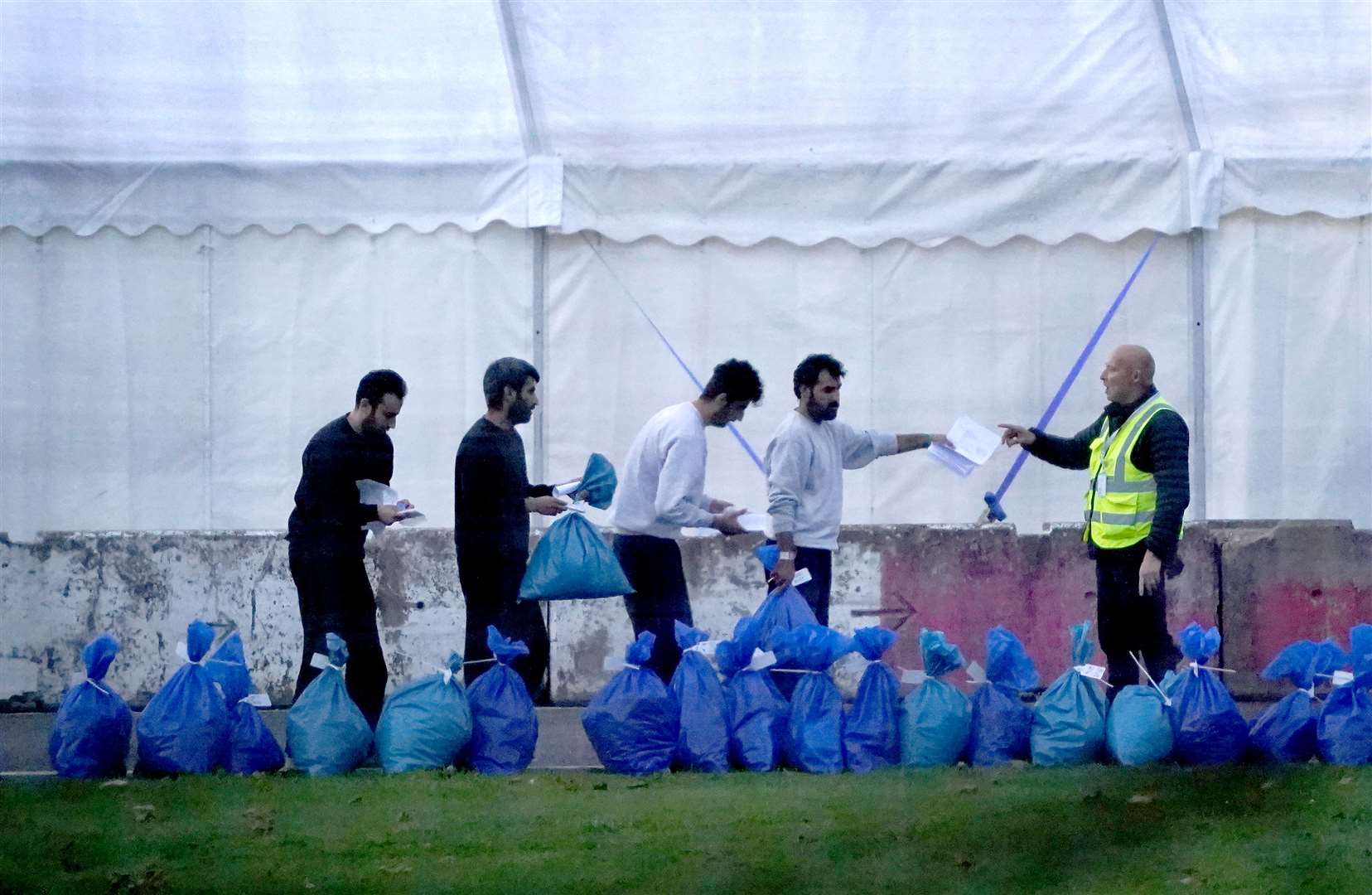 A group of people thought to be migrants gather their belongings before leaving the Manston immigration short-term holding facility (Gareth Fuller/PA)