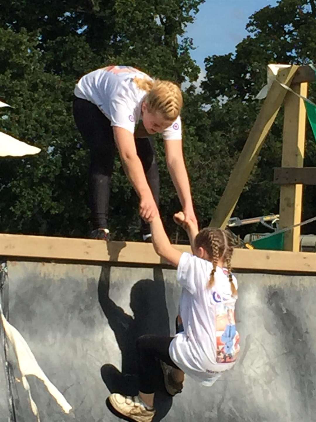 Eryn, 12, helping her sister Brooke, eight, up the final ramp of the Mini Mudder. Picture: RAF Benevelant Fund