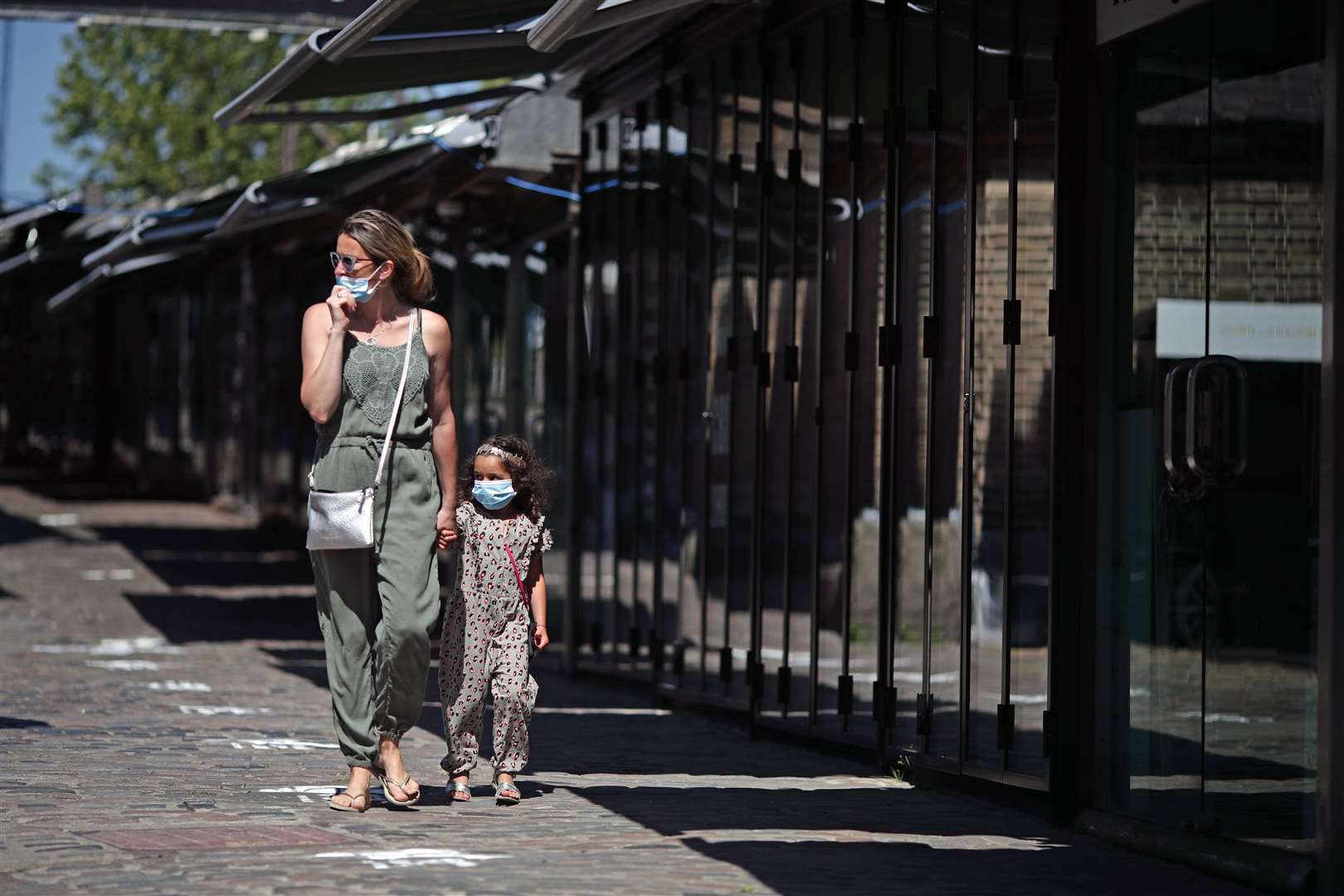 A woman and child walk through Camden Market in north London, which has reopened (Aaron Chown/PA)