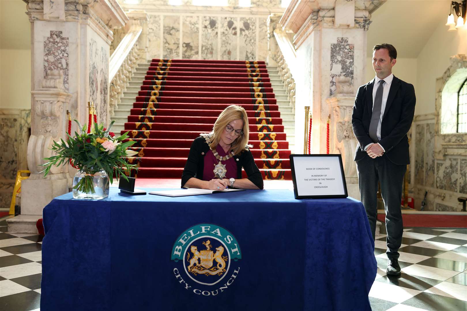The Lord Mayor of Belfast Tina Black signs a book of condolence watched by Laurence Sims, Joint Secretary to the Irish Secretariat in Belfast (Belfast City Council/PA)