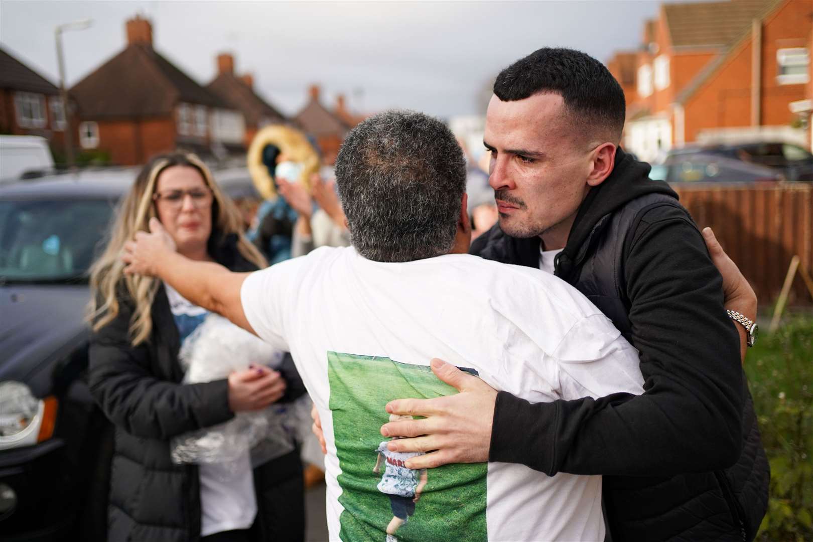 Family and friends embrace in the street (Jacob King/PA)