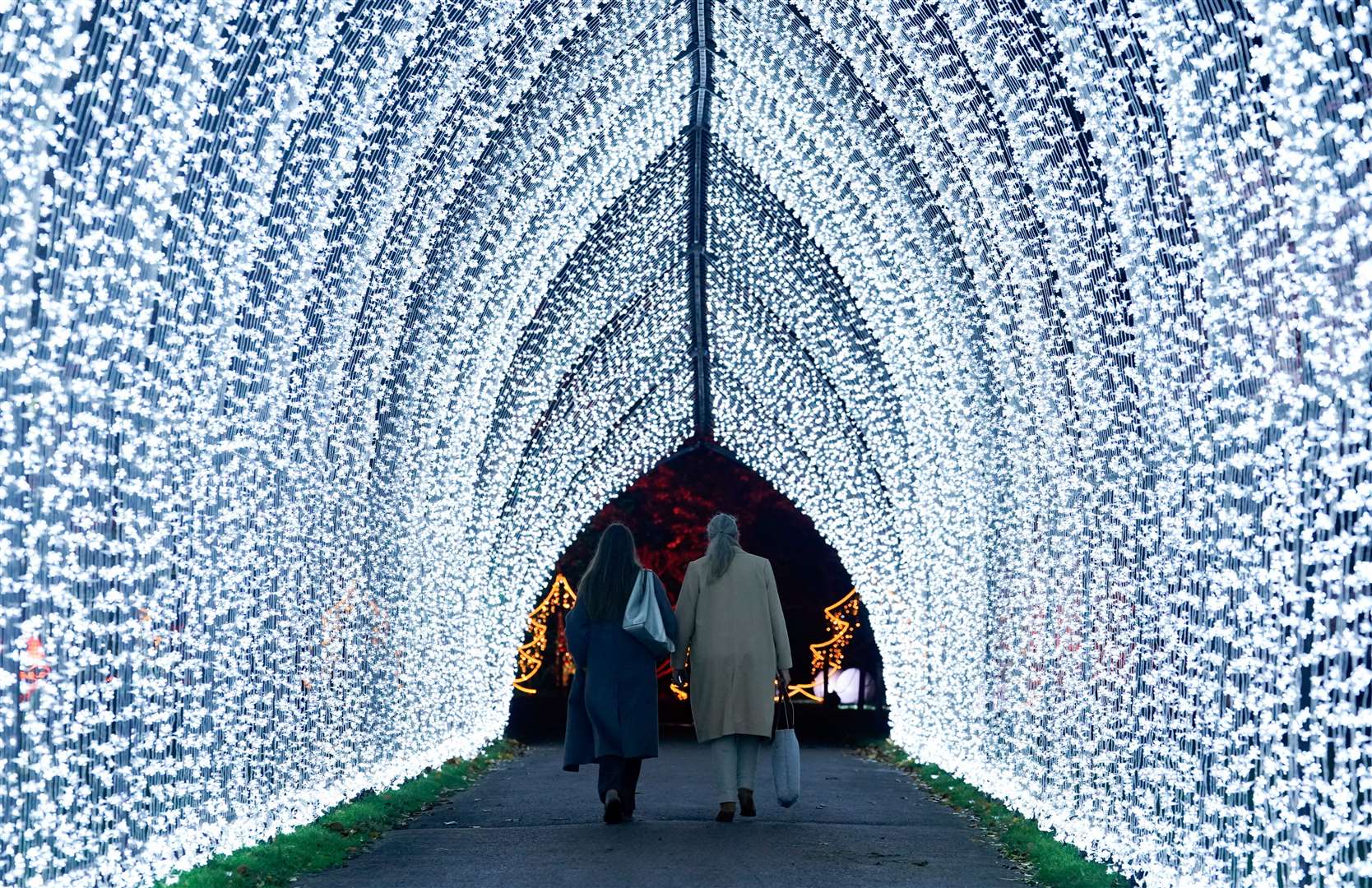 People walking through an illuminated archway during a preview of the Christmas at Kew festive trail, at the Royal Botanic Gardens in Kew, London (Andrew Matthews/PA)