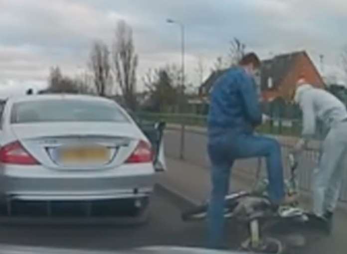 The Mercedes driver is seen pushing the motorcycle over and standing on it after the biker appears to try and get away