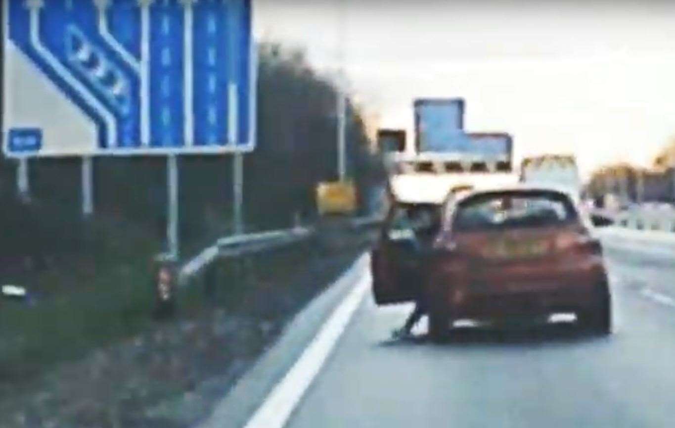 The footage shows someone trying to climb out of the passenger side of the car as it is moving along the M20