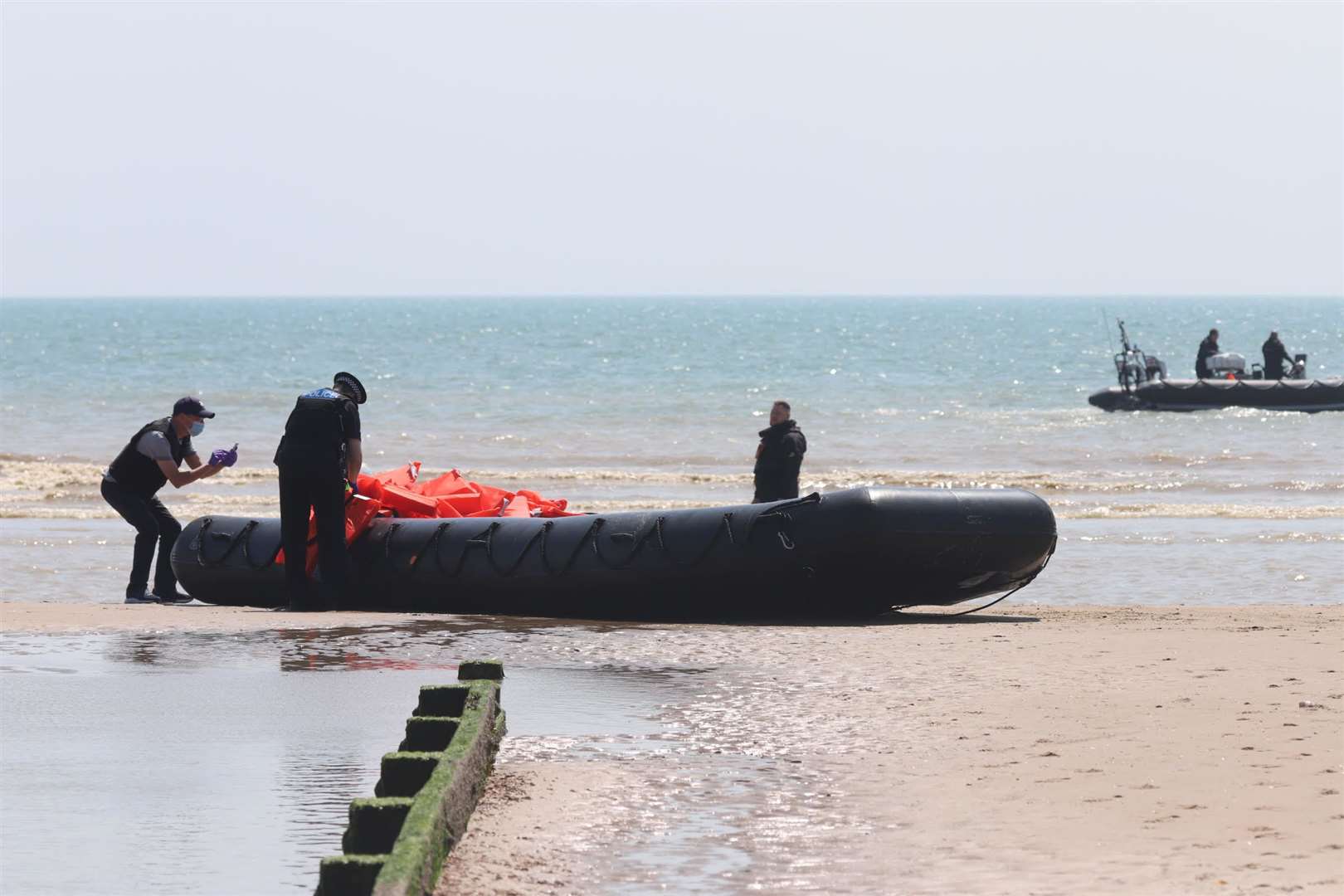 Police and officials examine one of the dinghies landed at Dymchurch. Submitted picture