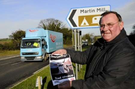 Cllr Nigel Collor holds a version of one of the posters to remind drivers not to overtake on the A258