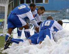 Gills players join Dennis Oli in the snow to congratulate him on his goal
