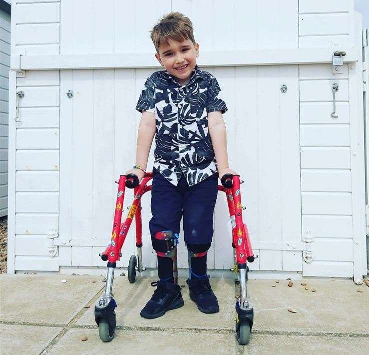 WALKING TALL: Harry Ragless has raised £2,400 with the help of his father and his walking frame and leg supports.