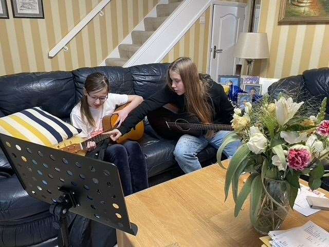 Olivia teaching Nastya a few chords on the guitar