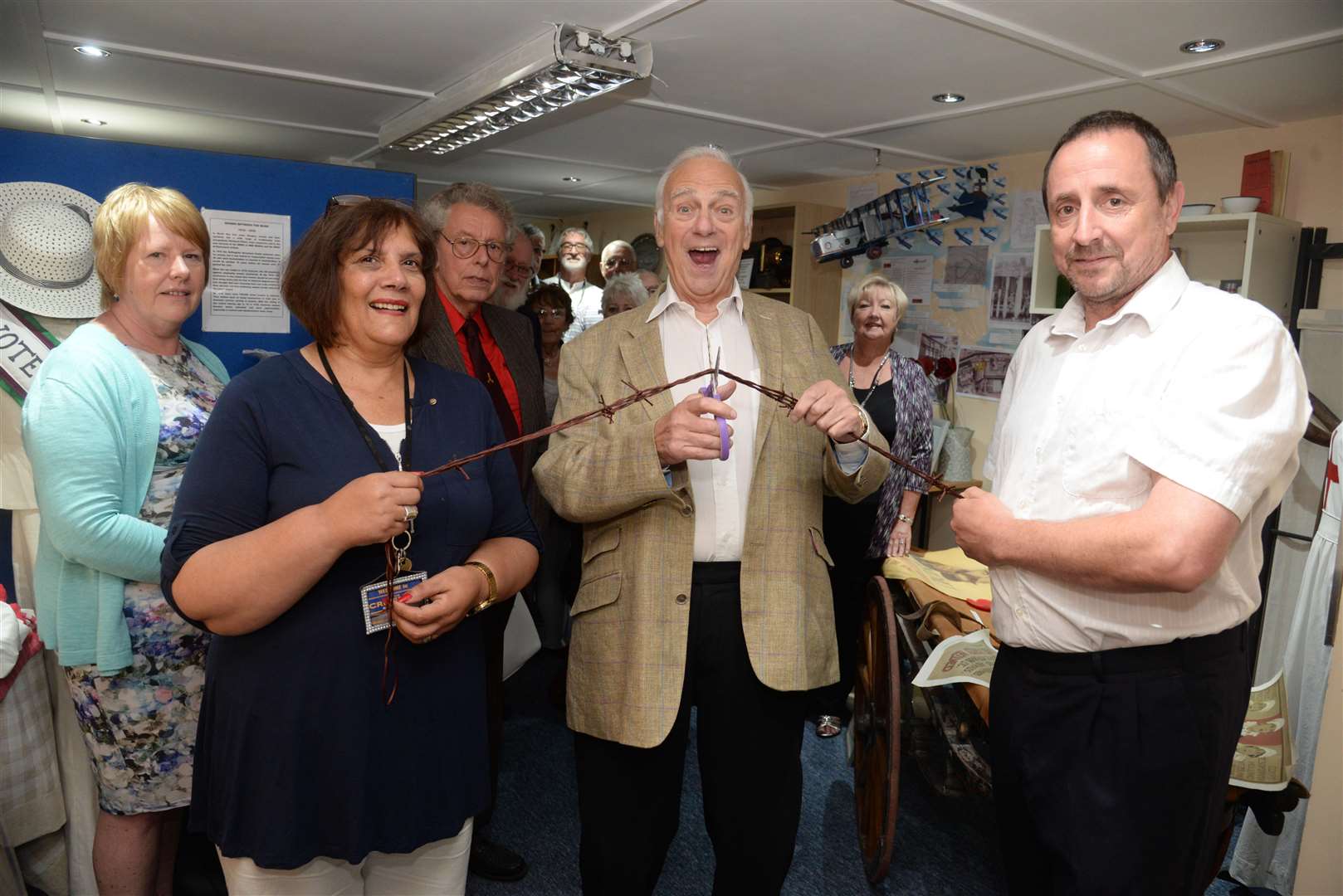 Jenny Hurkett and volunteer John Vernel hold the 'barbed wire' ribbon as veteran comic Roy Hudd opens the new floor and display at the Blue Town Heritage Centre, Sheerness on Thursday. Picture: Chris Davey. (2562242)