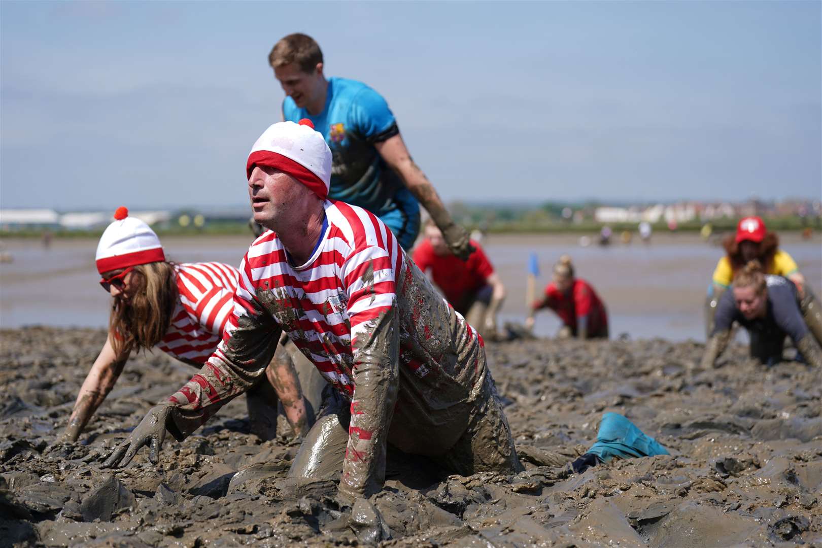 A woman and man, dressed as Wally from the Where’s Wally? books, take part in the annual Maldon Mud Race, a charity event to race across the bed of the River Blackwater in Essex, in May (PA)