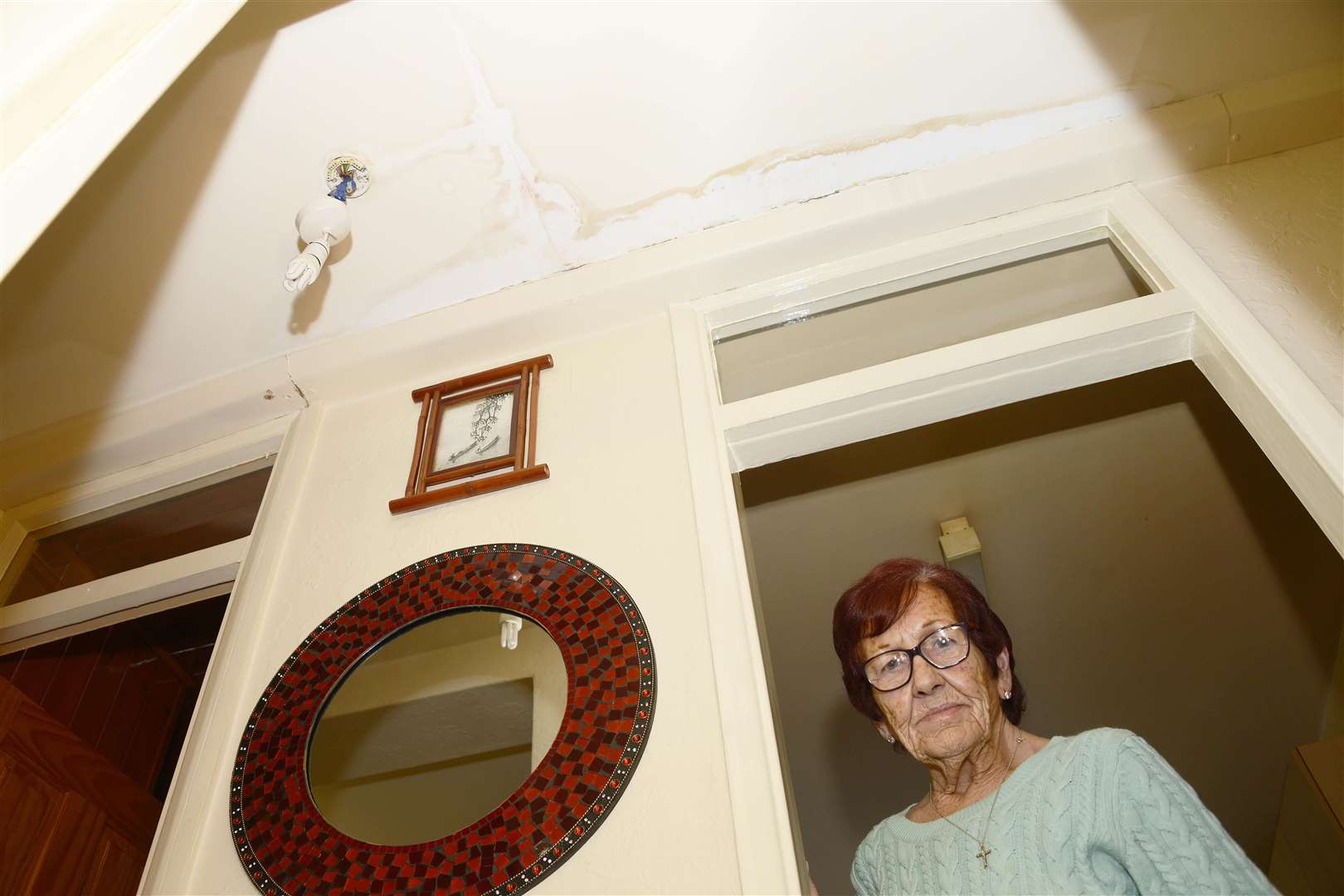 Theresa Tait with her buckets to catch water and the stains on the ceiling. Picture: Paul Amos