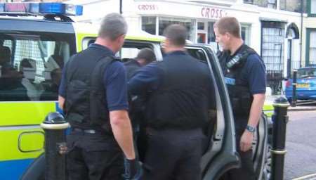 Police officers place one of the suspects into a waiting vehicle. Picture: GRAHAM TUTTHILL