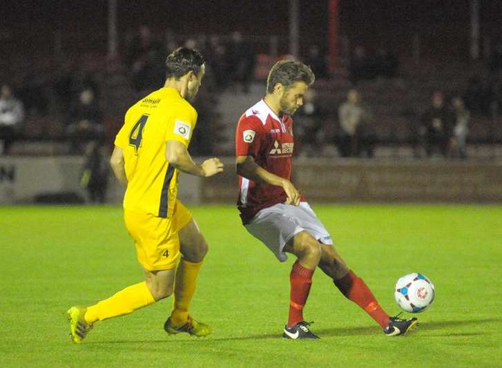 Daryl McMahon chips the ball forward under pressure from Eastbourne's Matt Aldred Picture: Steve Crispe