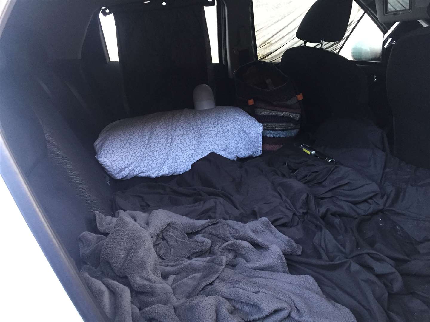 An air bed has been wedged into the back seat of a car