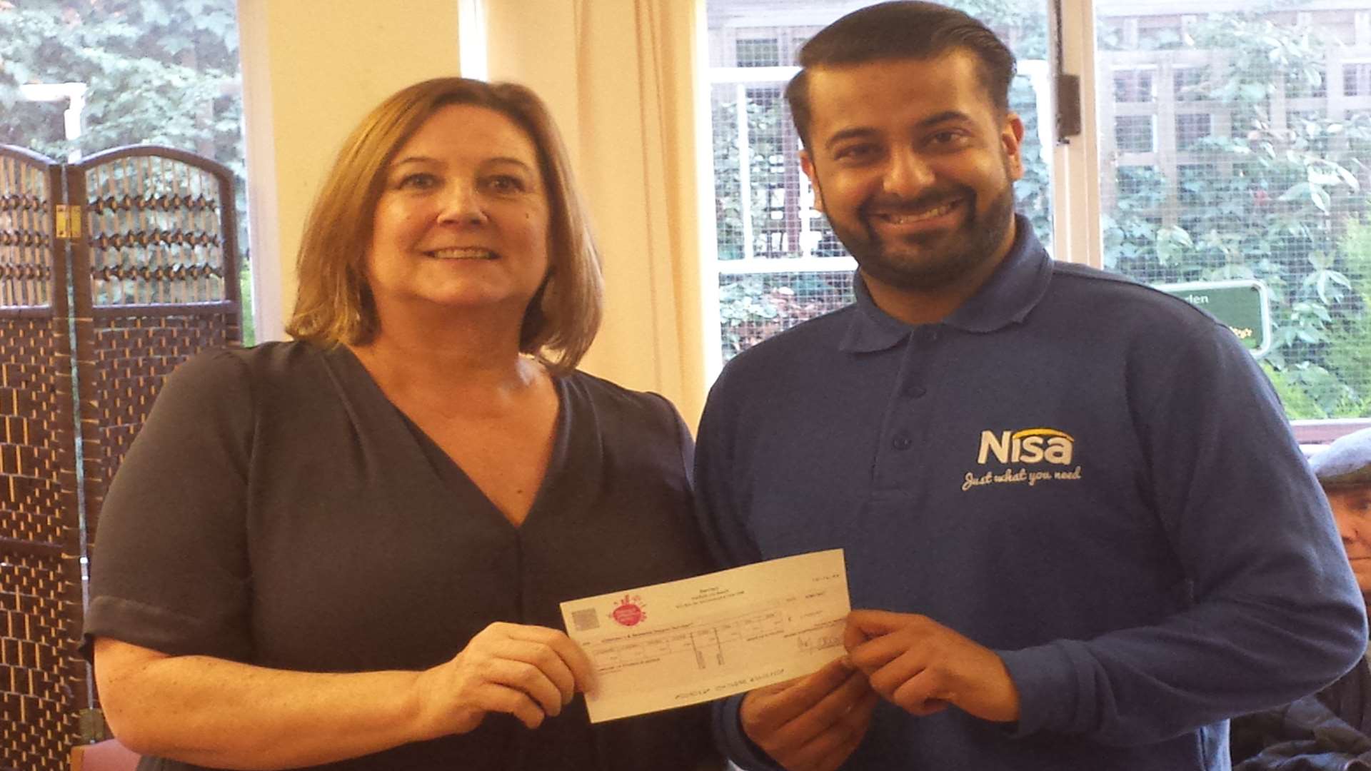 Jazz Goraya from Nisa presents the cheque to day care manager Lynn Lidstone