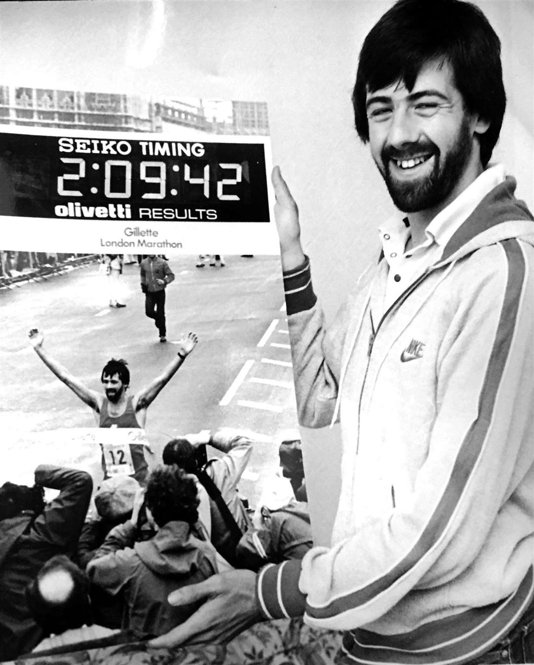 Mike Gratton poses with a picture of him crossing the finishing line