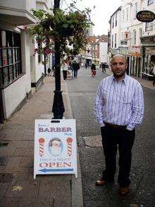 Barber shop owner Fuat Kutukcu with his advertising A-Board