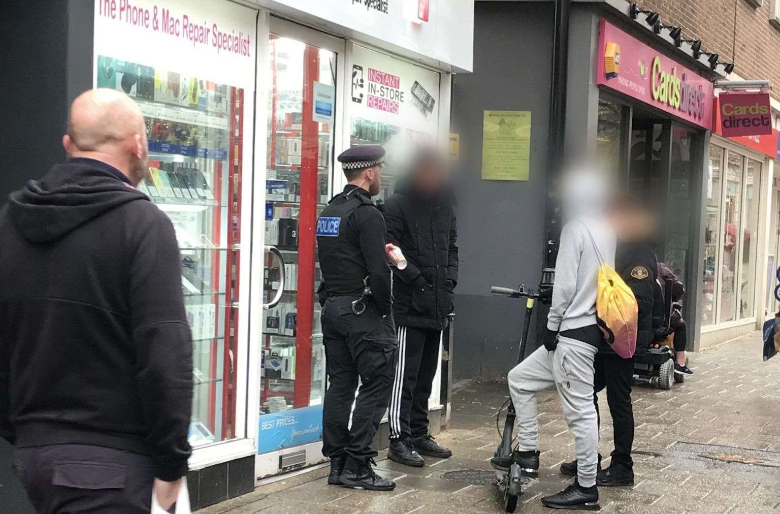A police officer stands talking to an e-scooter rider in Canterbury