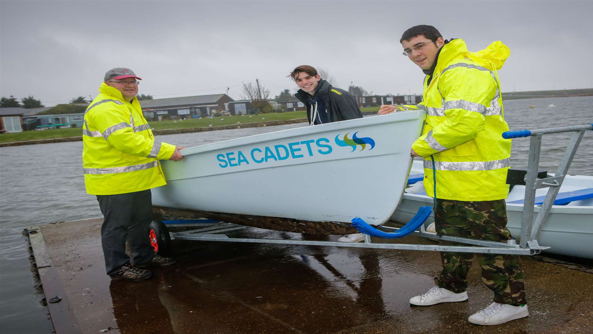 Commanding Officer Lt Brian Moore, Able Cadet Jamie Brown, and Petty Officer Kieron Hughes pull a Trinity 500 rowing boat out of the water