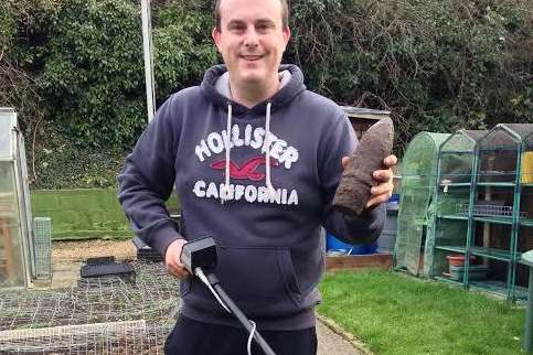 Gary Underdown with his metal detector and the WWII shell he unearthed