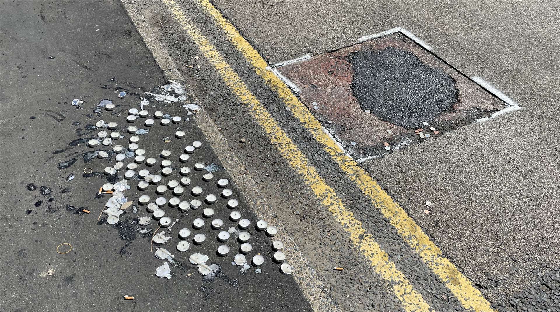 Candles have been left by a recently patched pothole close to the tributes
