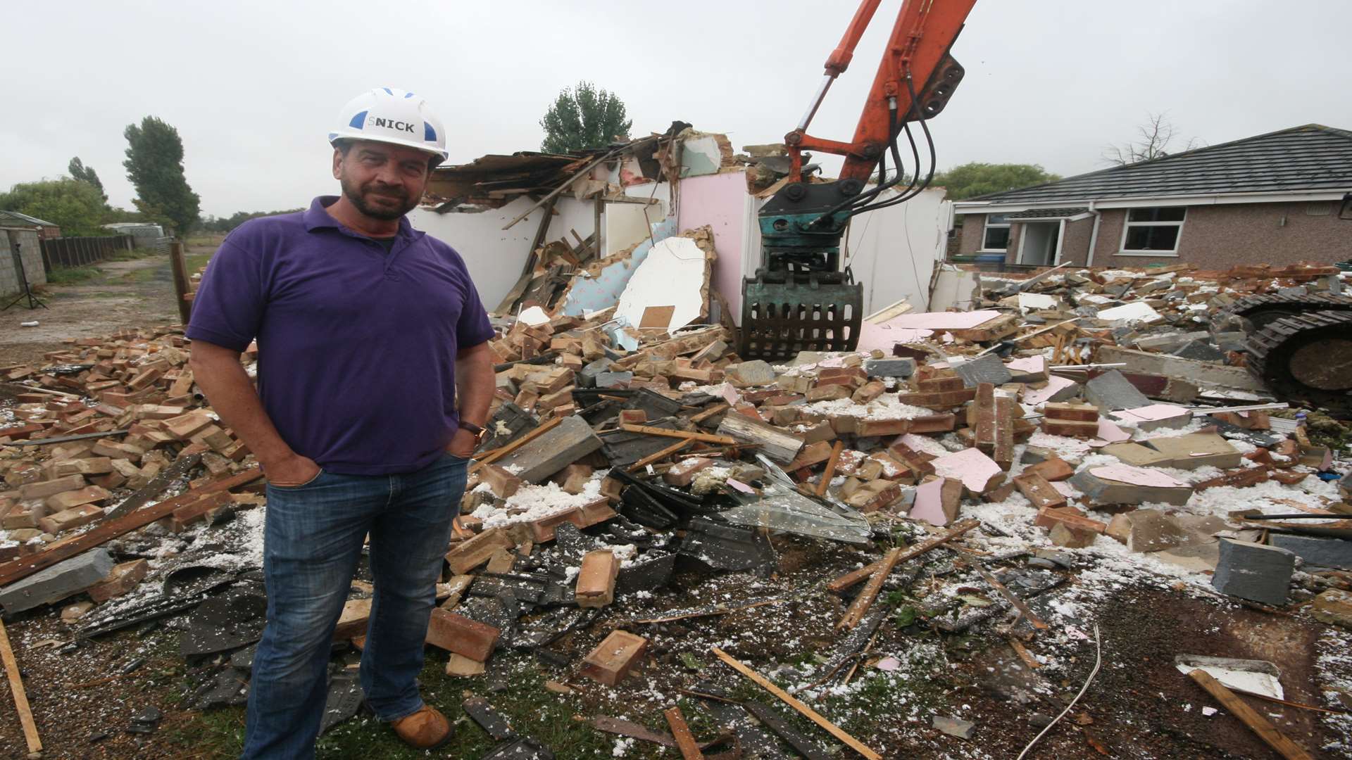 Watch it come down: DIY SOS presenter Nick Knowles amid the rubble of the original bungalow