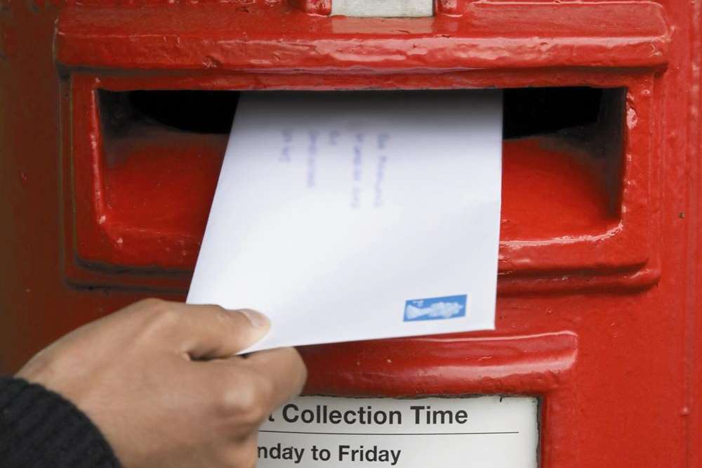 Letter being posted in a traditional British red post box