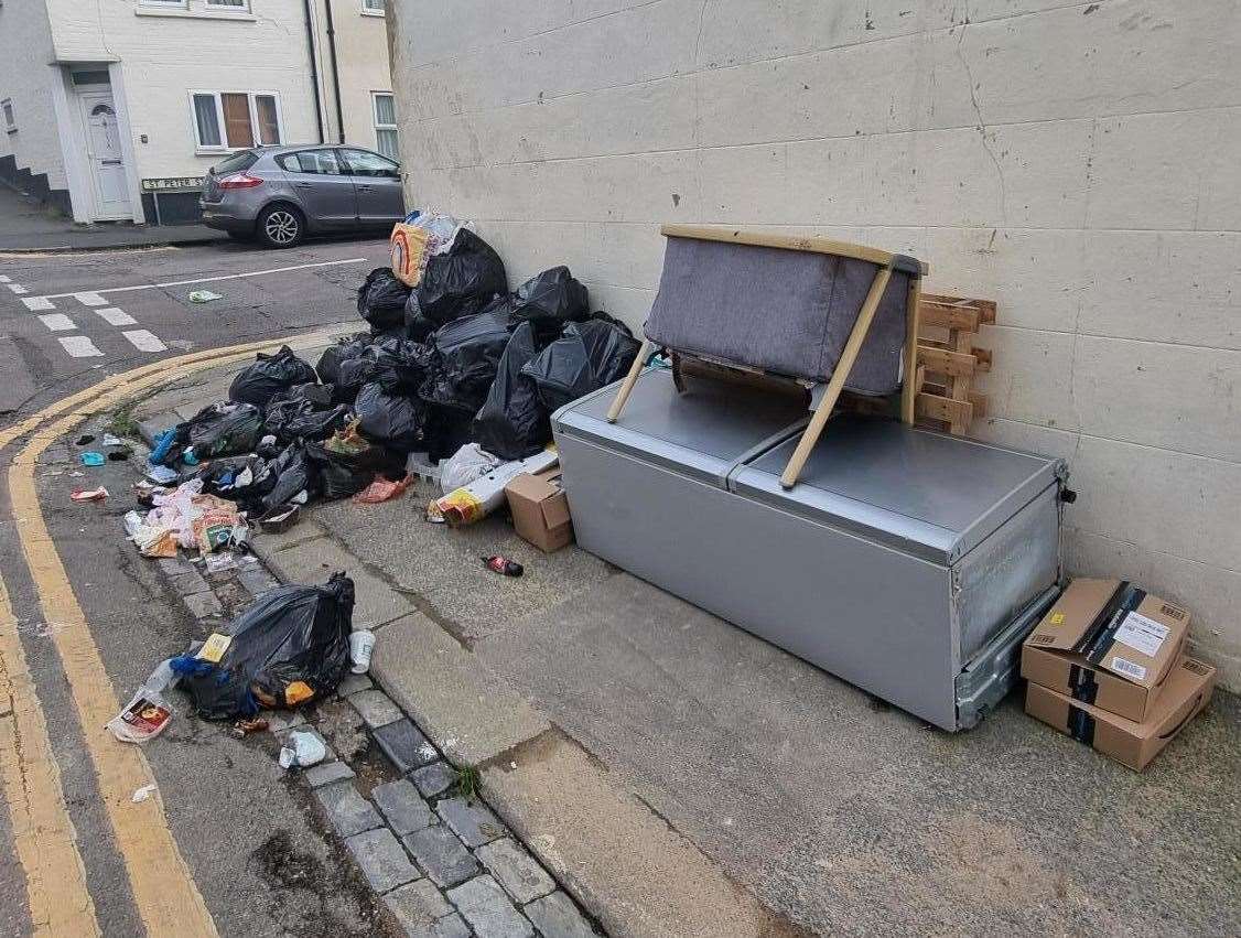 Black bin bags and furniture dumped on the side of the street