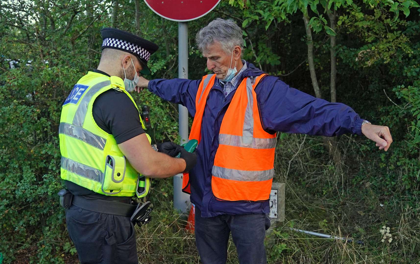 A police officer searches a protester at a slip road at junction 18 of the M25, near Rickmansworth (Steve Parsons/PA)